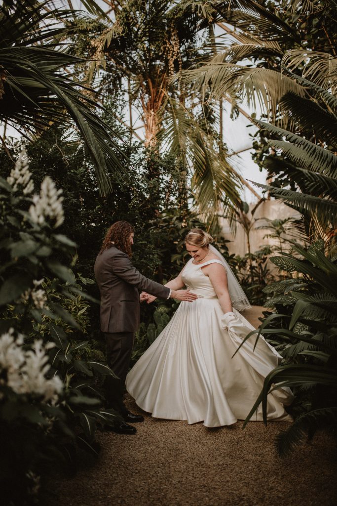 couple posing in a botanical garden in wedding attire