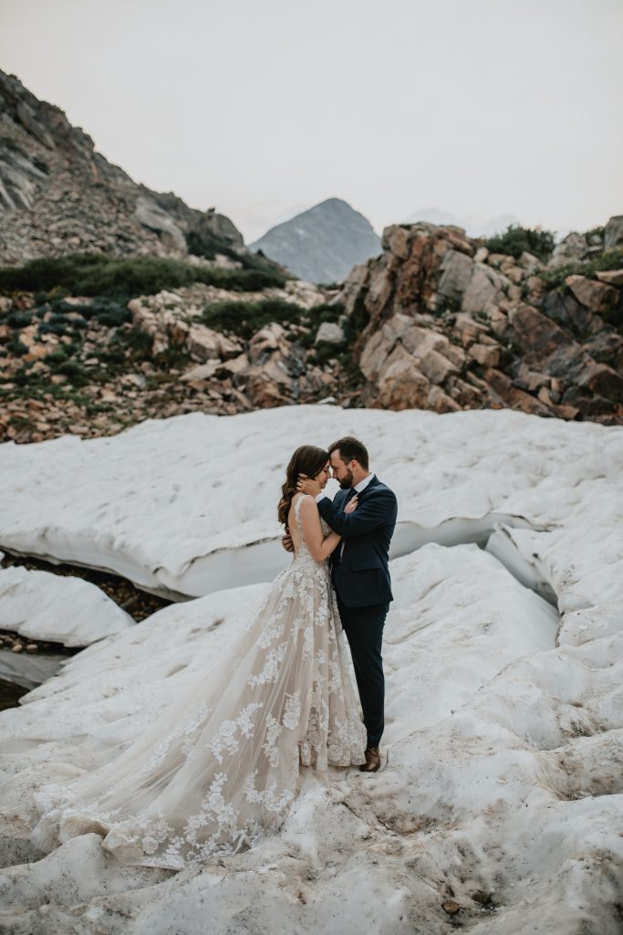 Couple in Colorado in wedding attire posing on top of a mountain