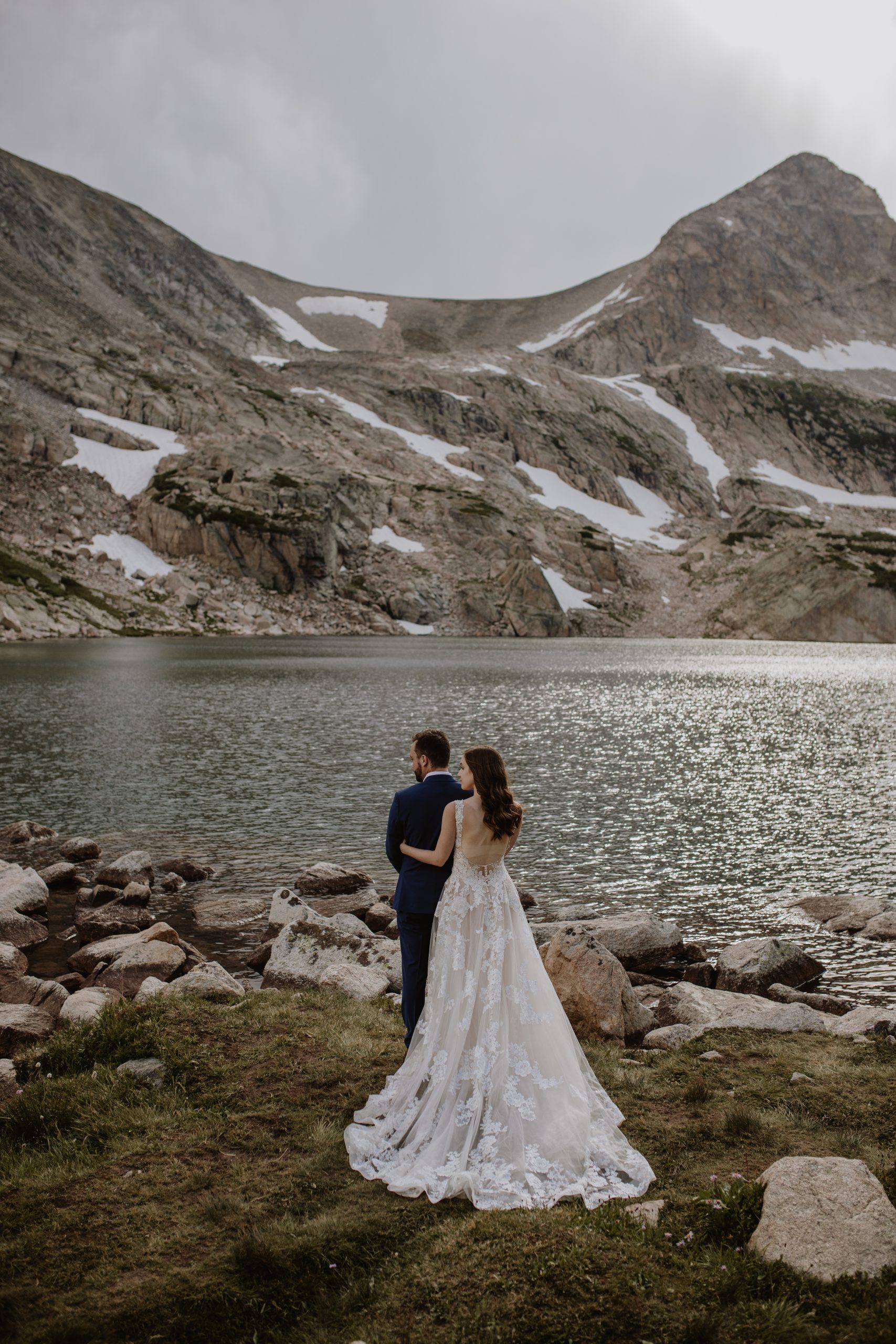 Couple in wedding attire posing in front of Colorado Mountains