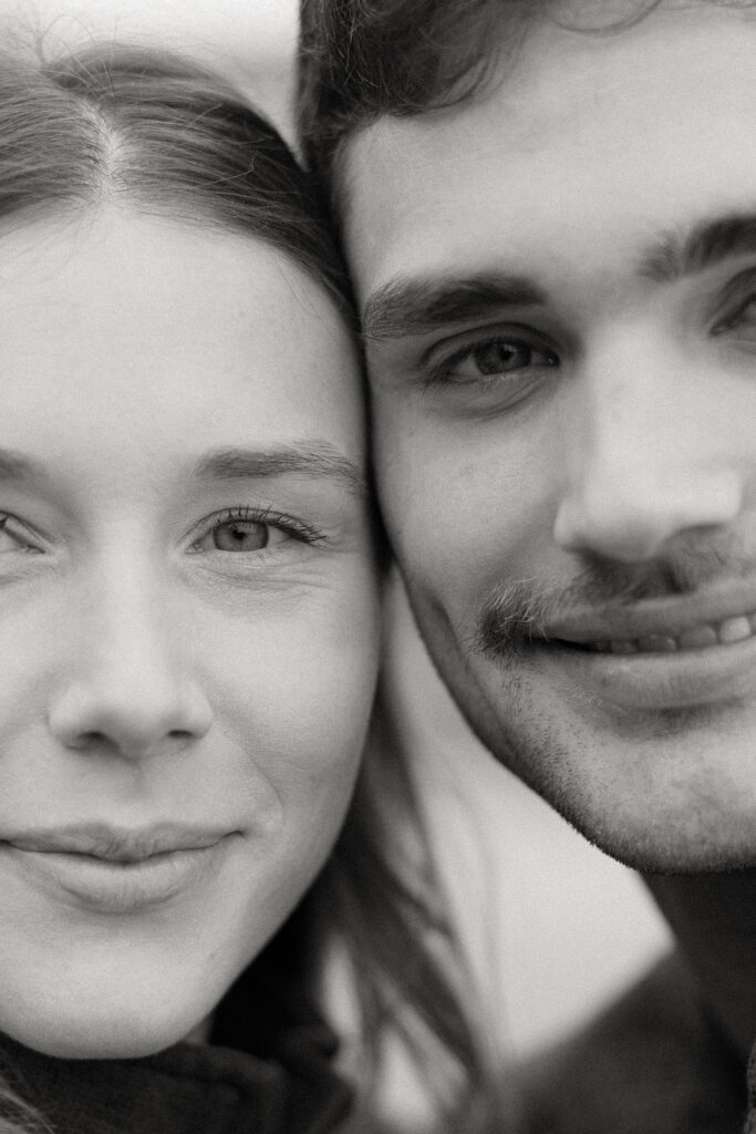A black-and-white close-up of a couple's faces, highlighting their eyes and soft smiles.