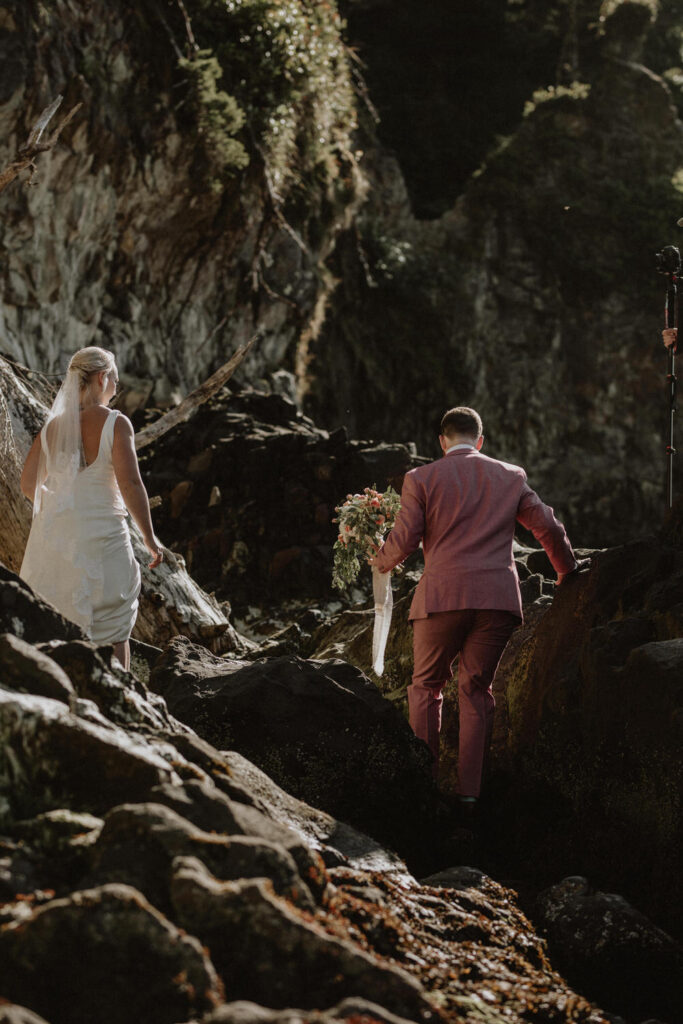A couple hikes up rocks on their elopement day.