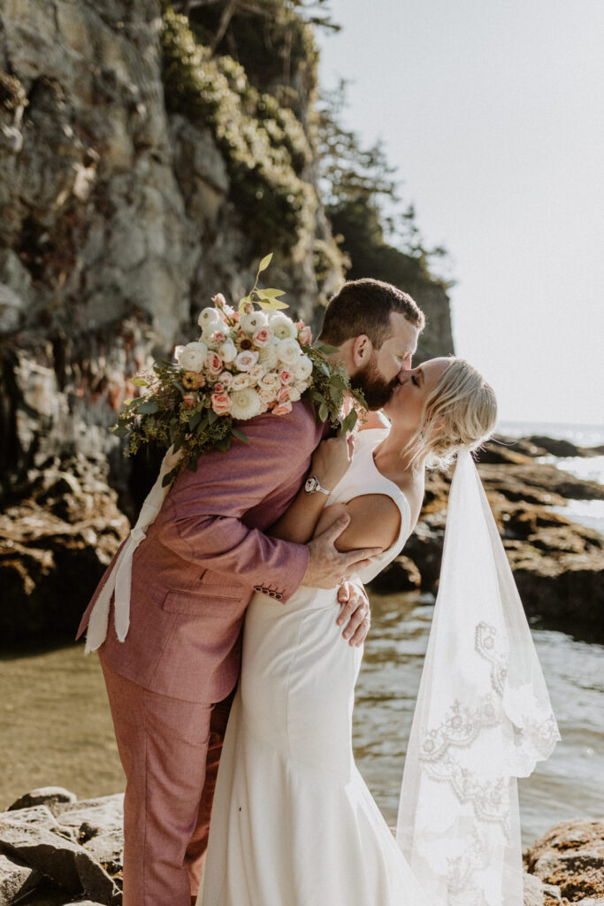 A married couple kisses one another on the Oregon beach.