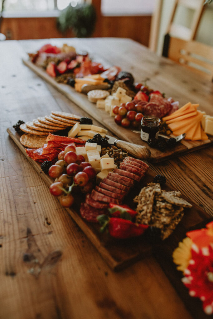 Charcuterie boards with grapes, berries, cheese, and more sits on a table.